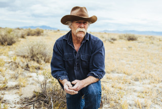 Dr. Eric Rickart kneels in a field while collecting mammal specimens. 
