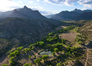 An aerial view of the Range Creek Field Station, which shows a lush valley and mountains at sunset.