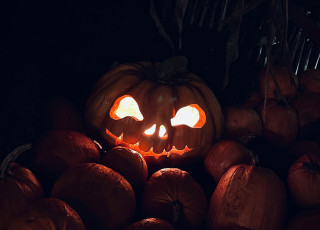 lit jack-o-lantern on a pile of pumpkins